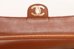 Close-up of CC gold hardware on interior flap on Chanel suede camel cognac quilted flap bag