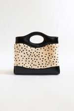 Back of Chanel mini shopping tote with ivory calf hair hand-painted cheetah dot print, black leather trim, structured top handle from Métiers d'Art 2026 collection by Matthieu Blazy 