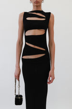 Close-up of black Christopher Esber ribbed sleeveless maxi dress with diagonal cutouts, form-fitting silhouette, and black Velvet Chanel mini vanity on chain 