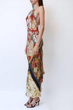 Vintage Salvatore Ferragamo halter gown with patchwork scarf print panels in red, gold, navy, and cream, featuring tiger, floral, and equestrian motifs, high halter neckline, and opaque silk back gathering detail. 