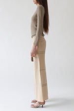 Left side view of a vintage Giorgio Armani taupe mohair crew neck sweater with long slim sleeves and rolled cuffs, styled with vintage Giorgio Armani sand flare trousers, the Row sandals, Loro Piana mini L19.