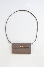 Front view of Hermès 2023 Kelly To Go in Etoupe leather with gold hardware and shoulder strap.