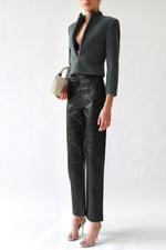 Black waxed TOTEME trousers with high waist and front seam detailing, styled with Emporio Armani cropped gray wool tailored jacket, black Prada nylon bralette, Galliano Dior bondage patent leather white top handle bag, and silver Miu Miu slingback heels  