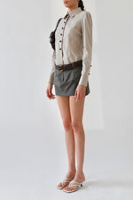 Side view of a vintage Gucci taupe pinstripe fitted blouse with brown knob buttons and a point collar, styled with grey Vivienne Westwood mini skirt, Saint Laurent brown leather belt, the Row kitten heels, and Miu Miu nappa leather shoulder bag.