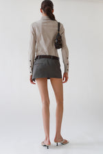 Rear view of a vintage Gucci taupe pinstripe fitted blouse with brown knob buttons and a point collar, styled with grey Vivienne Westwood mini skirt, Saint Laurent brown leather belt, the Row kitten heels, and Miu Miu nappa leather shoulder bag.
