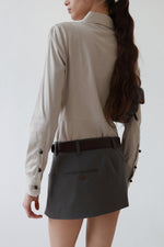 Side rear view of a vintage Gucci taupe pinstripe fitted blouse with brown knob buttons and a point collar, styled with grey Vivienne Westwood mini skirt, Saint Laurent brown leather belt.